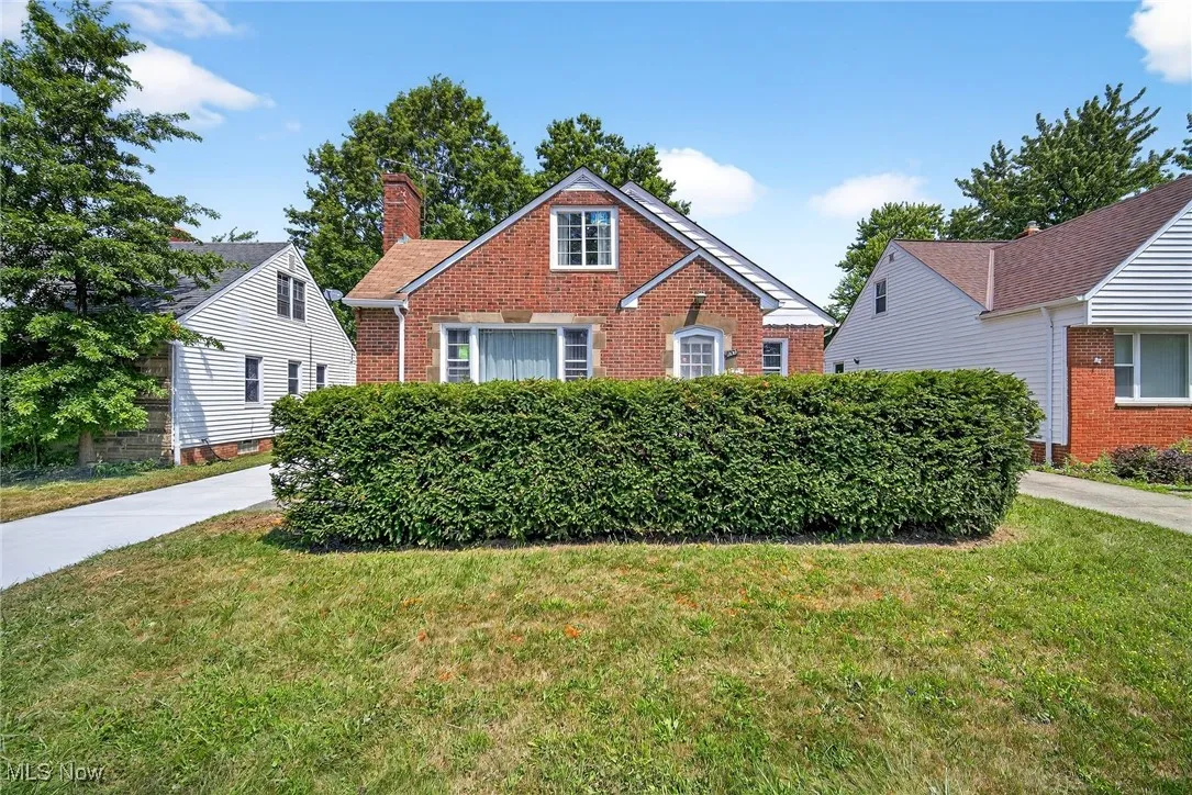 View of front of home with brick siding, a front yard, and a chimney