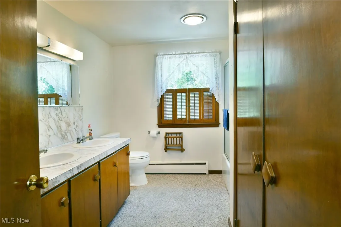 Full bathroom featuring baseboard heating and double vanity