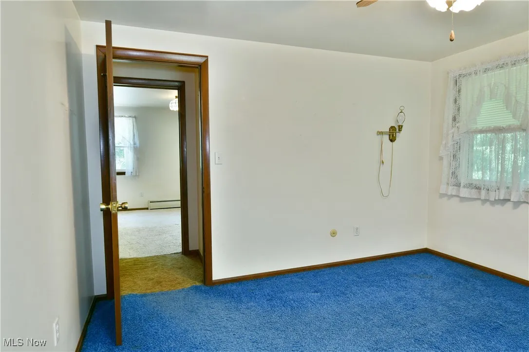 Spare room featuring carpet, a baseboard radiator, and ceiling fan