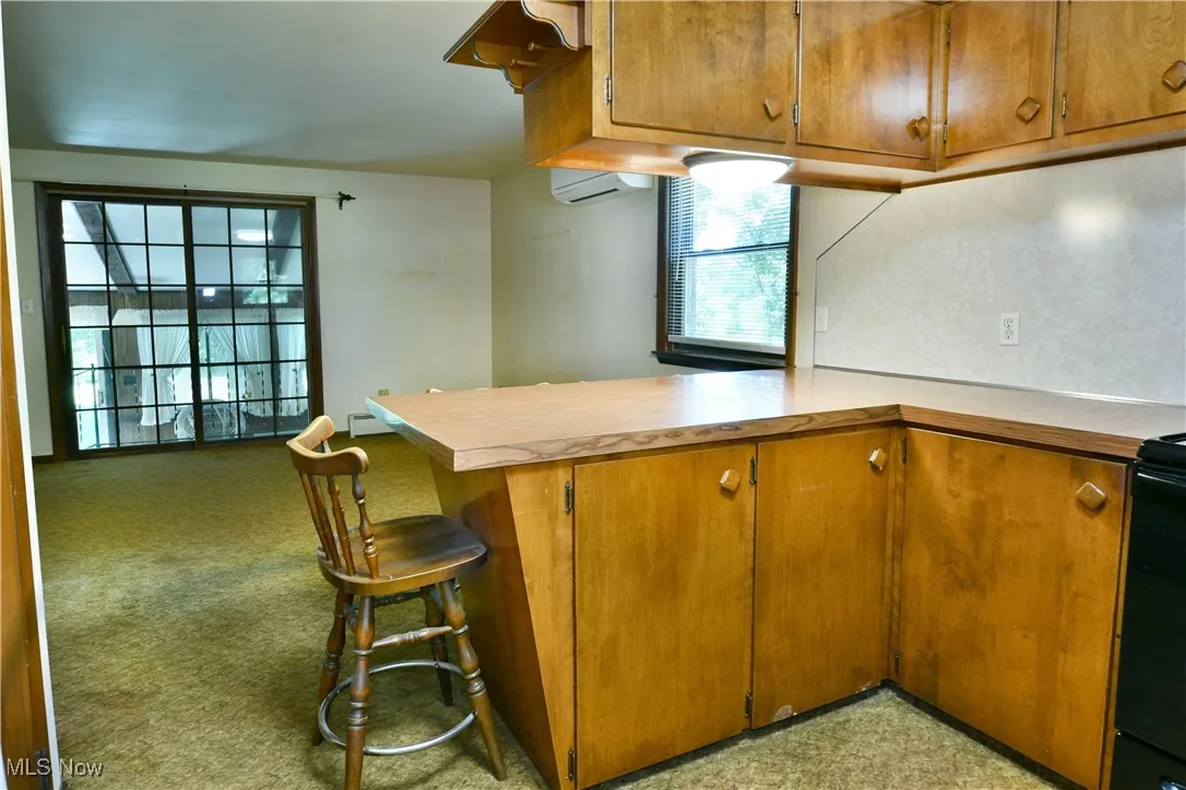 Kitchen with a peninsula, brown cabinetry, light countertops, and range