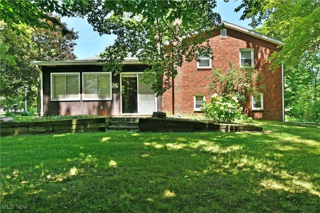Split level home featuring brick siding, entry steps, and a front lawn
