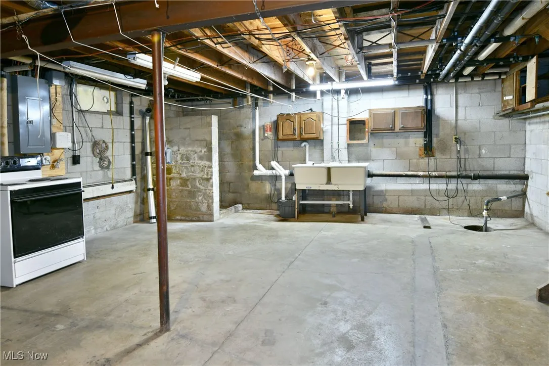 Unfinished below grade area featuring electric panel and washer / dryer
