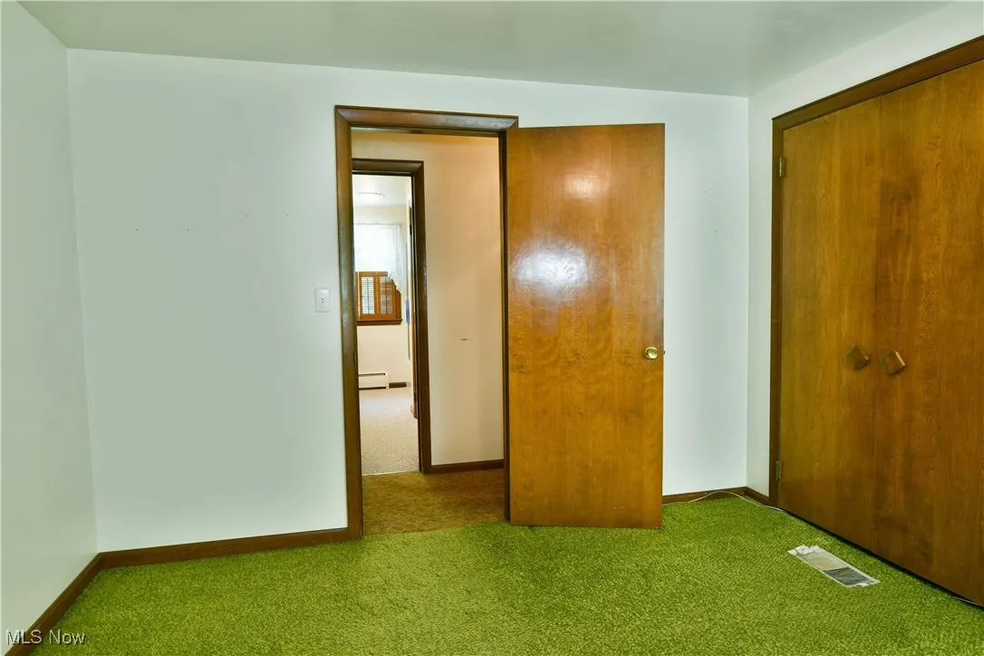 Unfurnished bedroom featuring carpet floors and baseboard heating