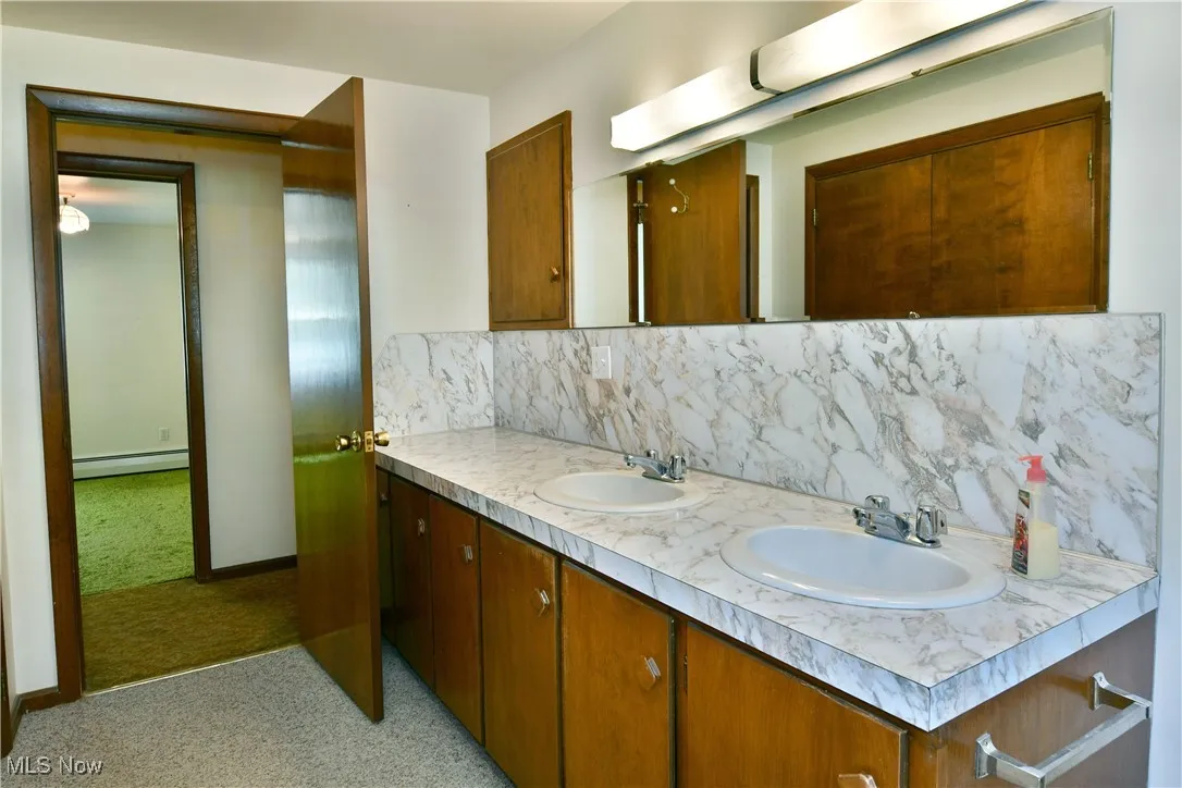 Bathroom featuring backsplash, double vanity, and baseboard heating