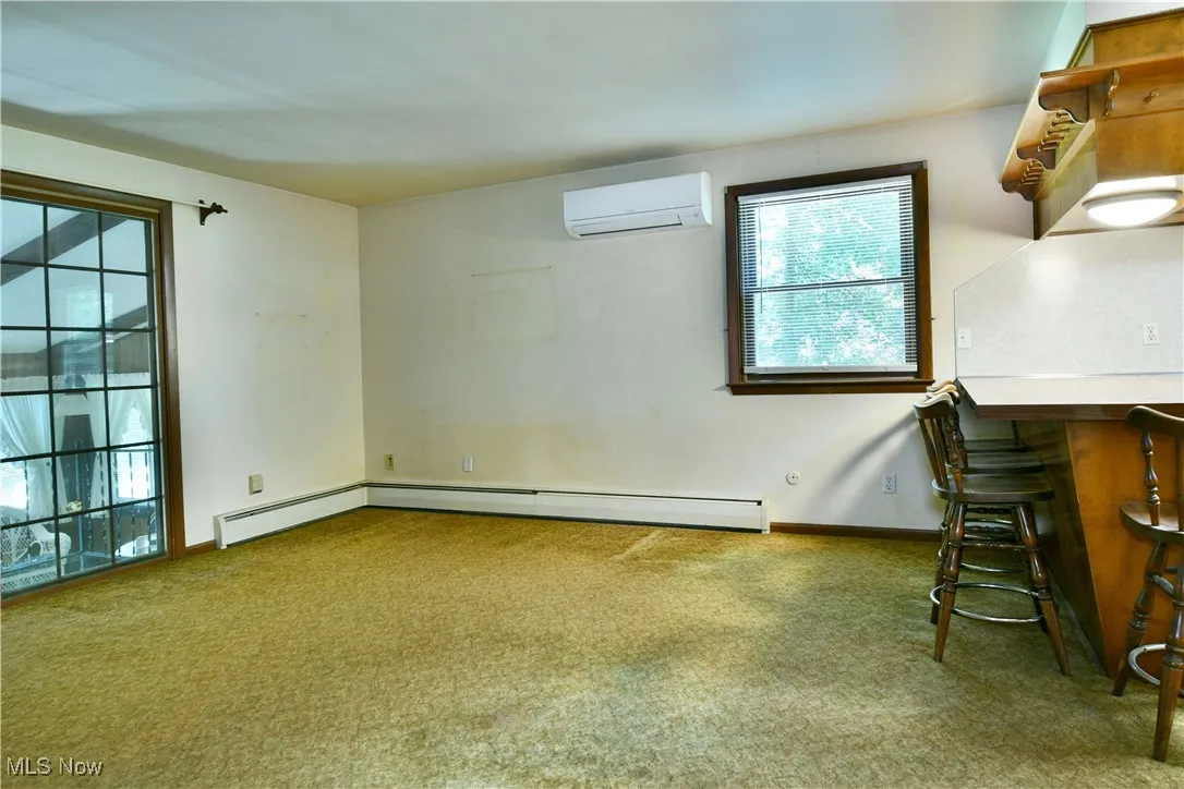 Carpeted spare room with an AC wall unit and baseboard heating