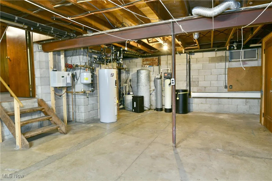 Unfinished basement featuring water heater, a water softener system, and stairs
