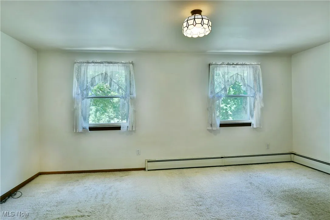 Empty room with carpet flooring and a baseboard heating unit