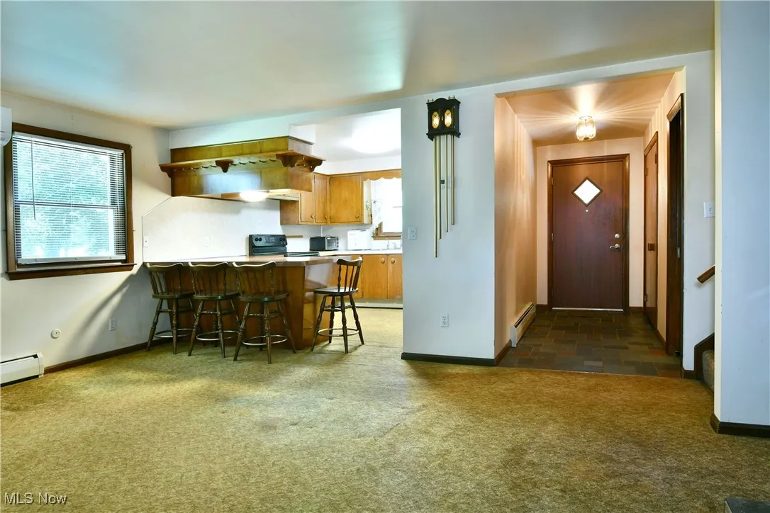 Kitchen with brown cabinetry, carpet, a breakfast bar, a peninsula, and a baseboard heating unit
