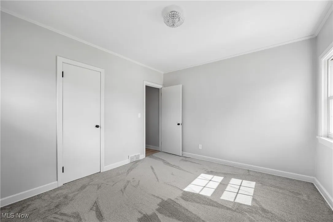 Unfurnished bedroom featuring carpet and crown molding