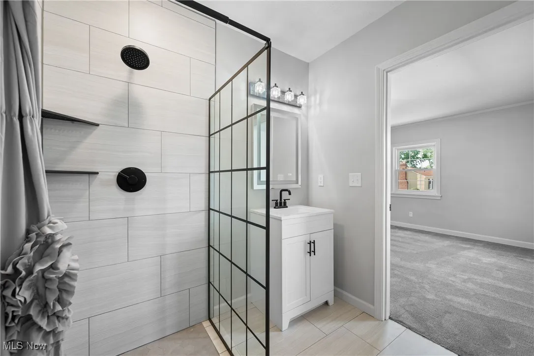 Bathroom featuring tiled shower, vanity, and tile patterned floors