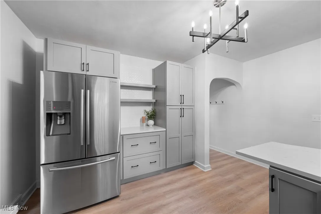 Kitchen with stainless steel fridge with ice dispenser, open shelves, light wood-type flooring, and gray cabinetry