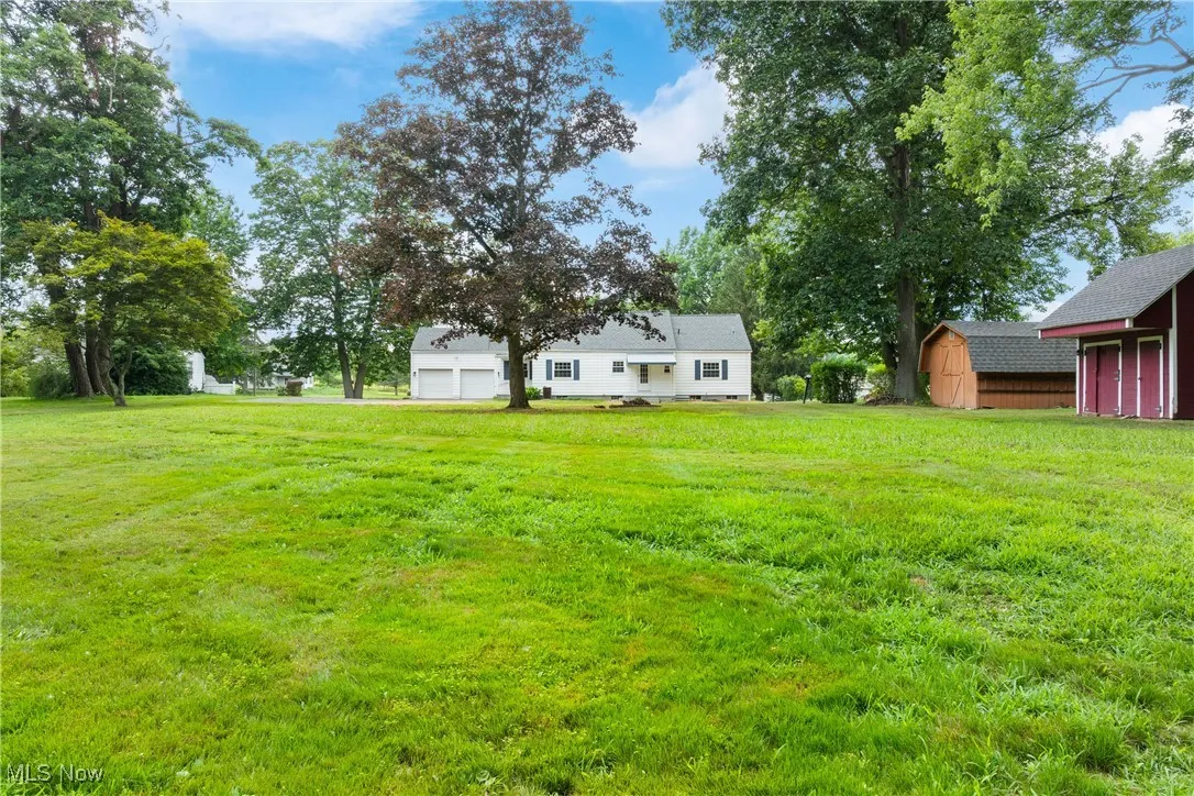 View of green lawn with a storage shed and a garage