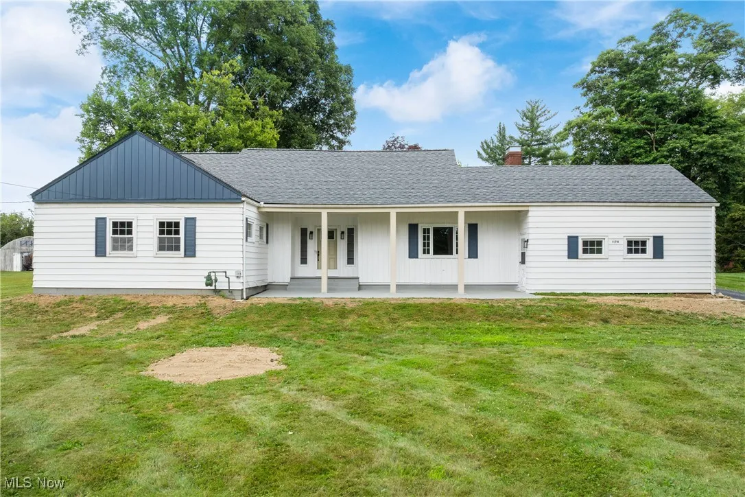 View of front of home featuring roof with shingles, a front lawn, a chimney, and board and batten siding