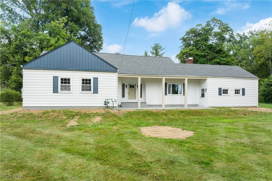 Rear view of house featuring a shingled roof, a yard, board and batten siding, covered porch, and a chimney