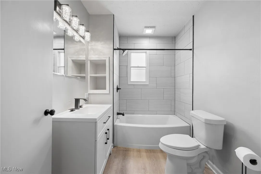 Bathroom featuring vanity, wood finished floors, shower / washtub combination, and a textured ceiling