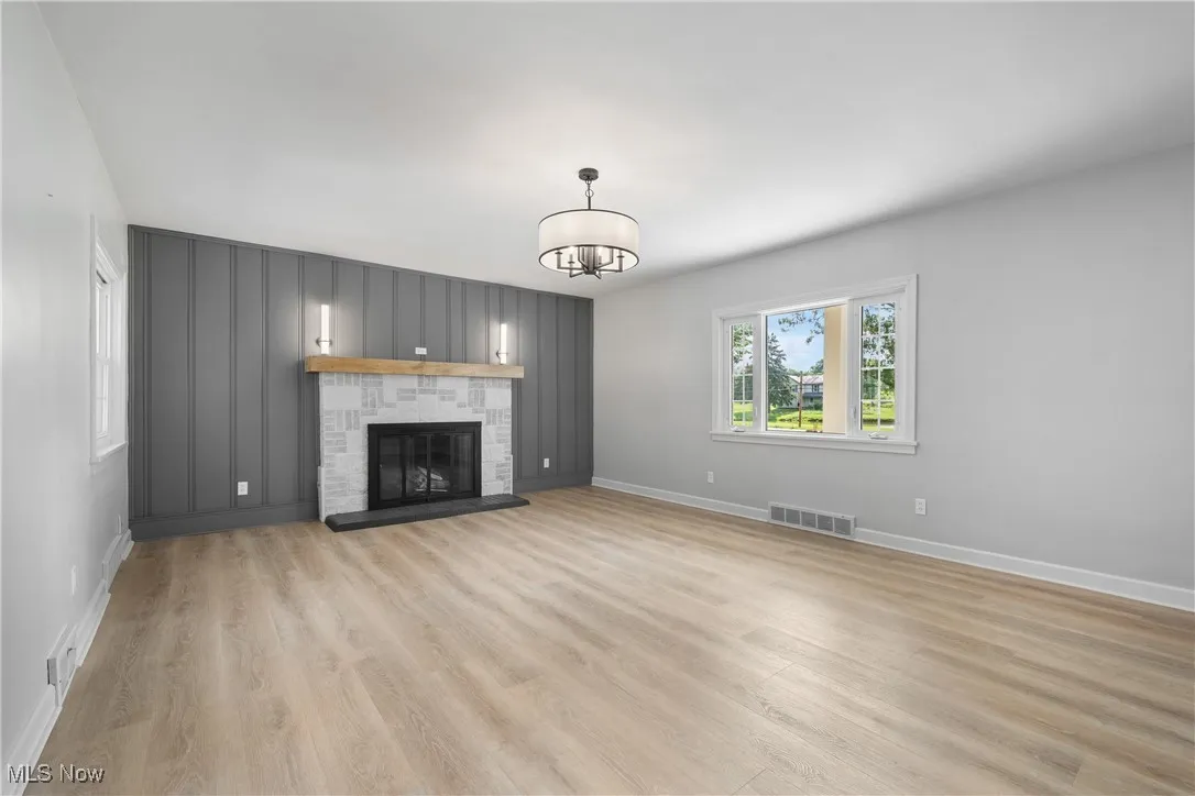 Unfurnished living room featuring a chandelier, light wood-style floors, and a fireplace