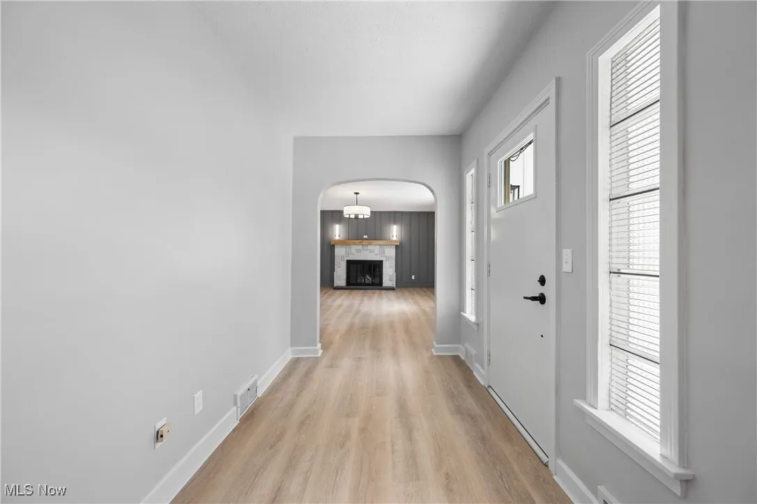 Foyer with arched walkways and light wood-style floors