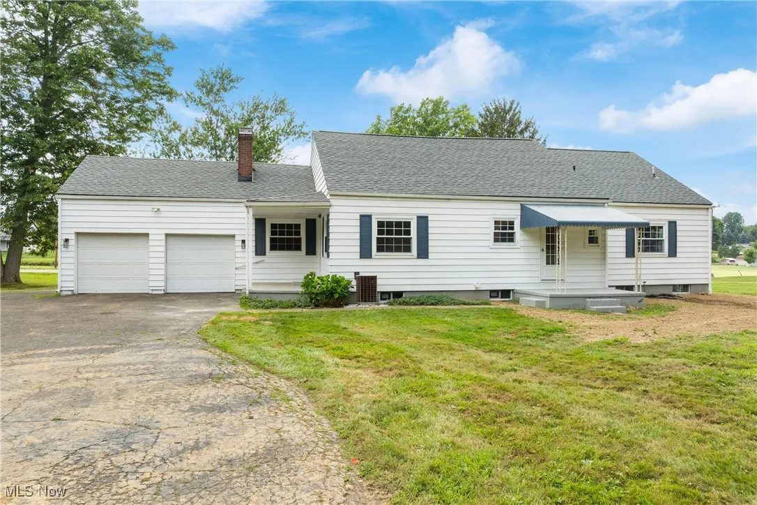 View of front of home with a chimney, driveway, a garage, a shingled roof, and a front lawn