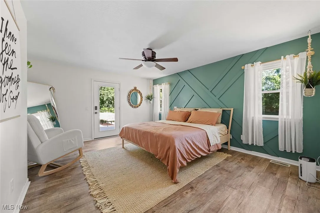 Bedroom featuring multiple windows, access to exterior, wood finished floors, and a ceiling fan
