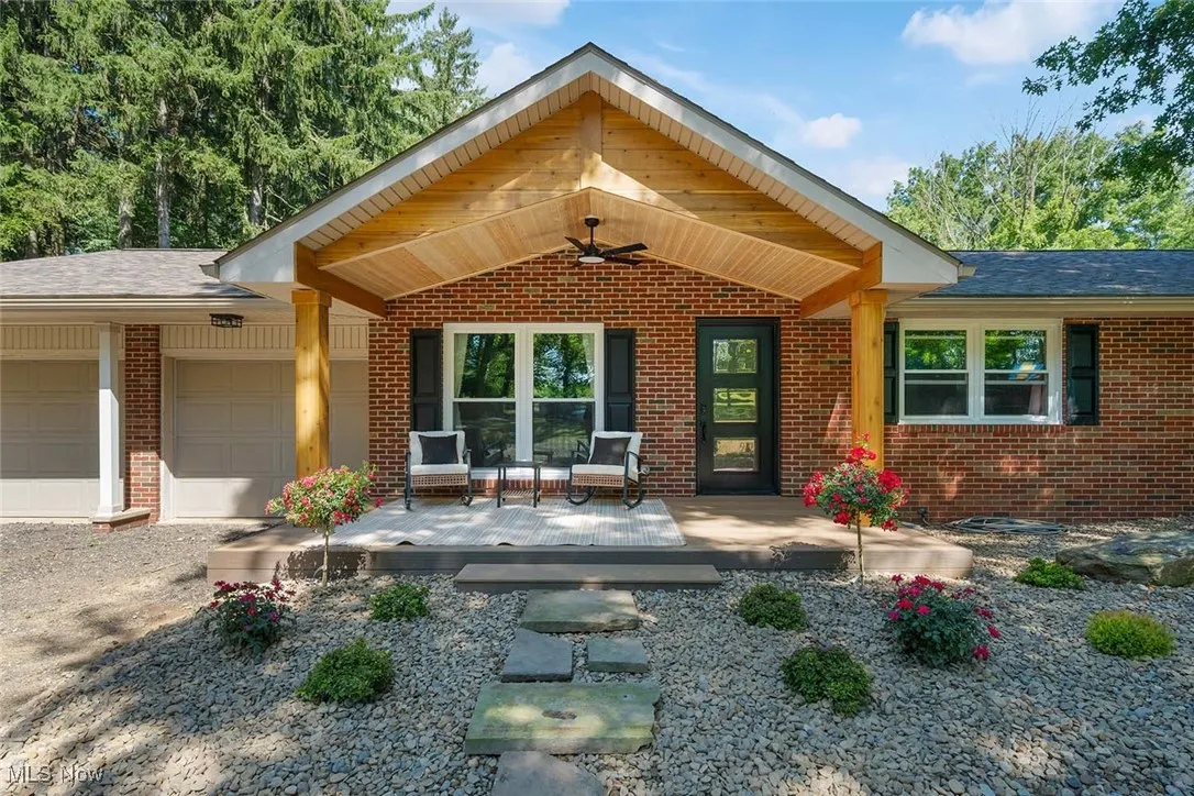 View of front of house featuring brick siding, a garage, and roof with shingles