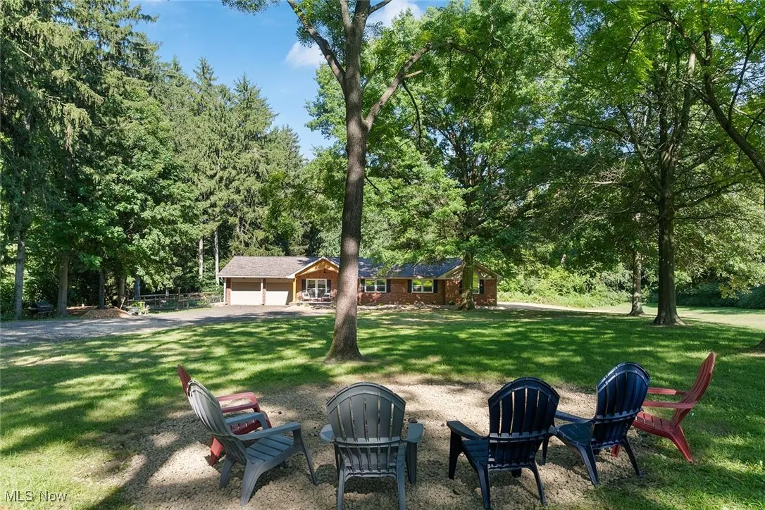 View of green lawn with a garage and a fire pit