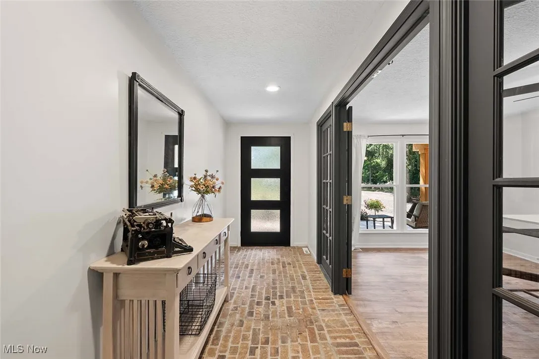 Entrance foyer with brick floors, a textured ceiling, and recessed lighting