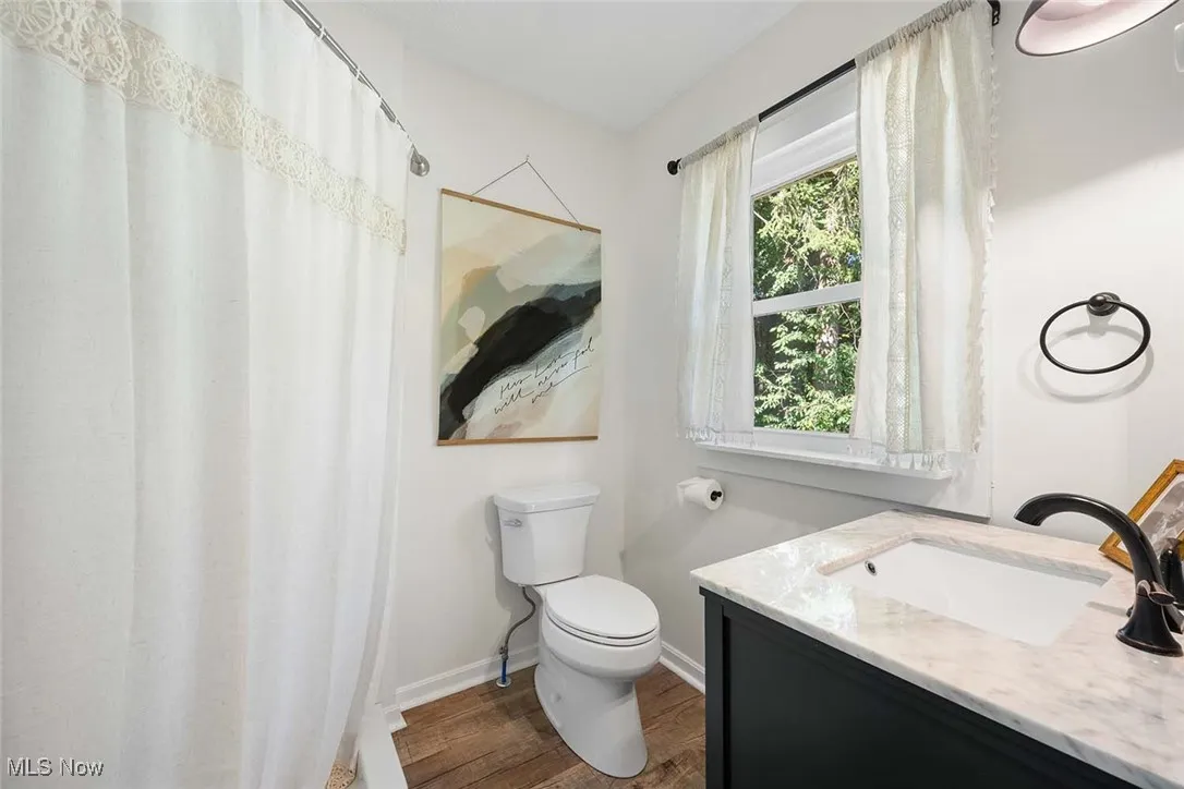 Full bath featuring wood finished floors, vanity, and curtained shower