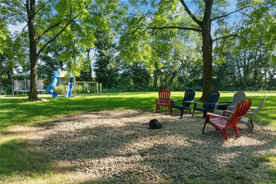 View of yard with a playground, a trampoline, and view of wooded area