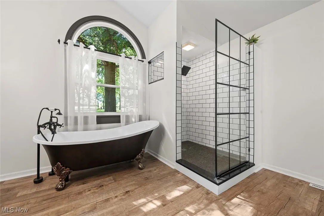 Full bathroom featuring a tile shower, a freestanding tub, and wood finished floors