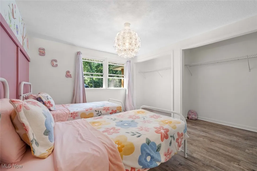 Bedroom with a textured ceiling, wood finished floors, and a chandelier
