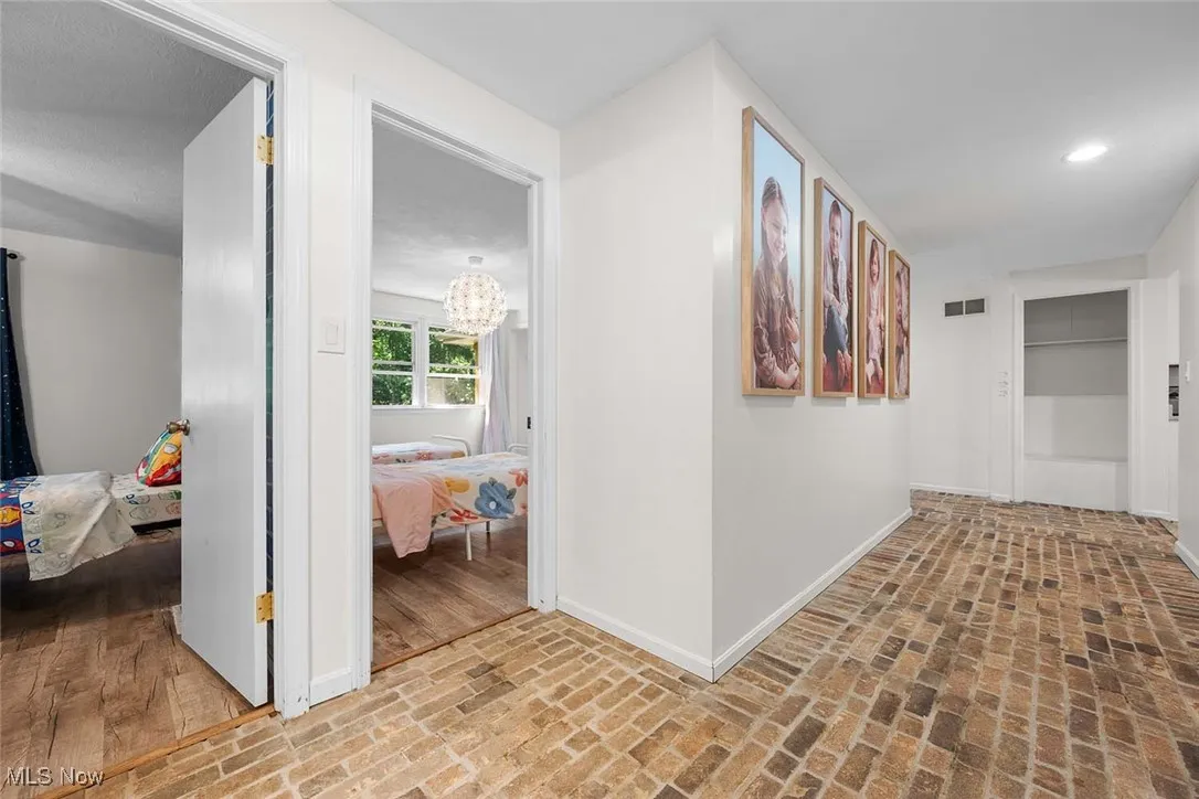 Hallway with brick flooring and a chandelier