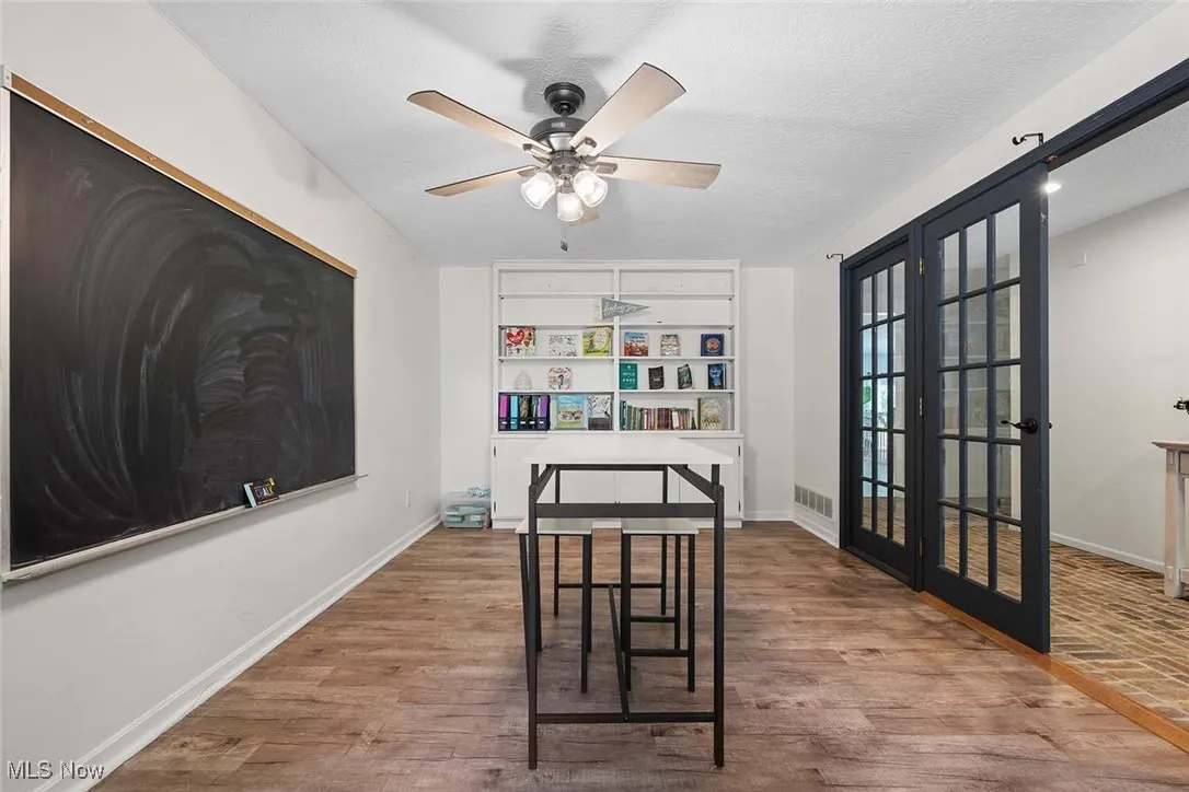 Dining room with french doors, wood finished floors, ceiling fan, and a textured ceiling