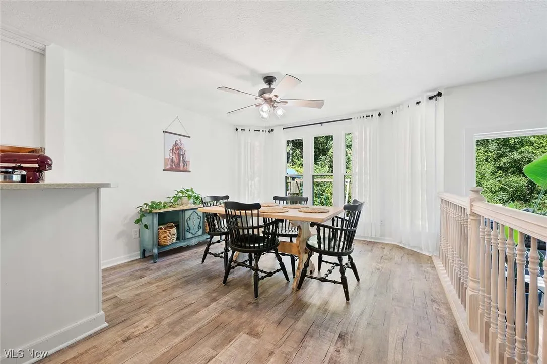 Dining space with a textured ceiling, a ceiling fan, and light wood-type flooring