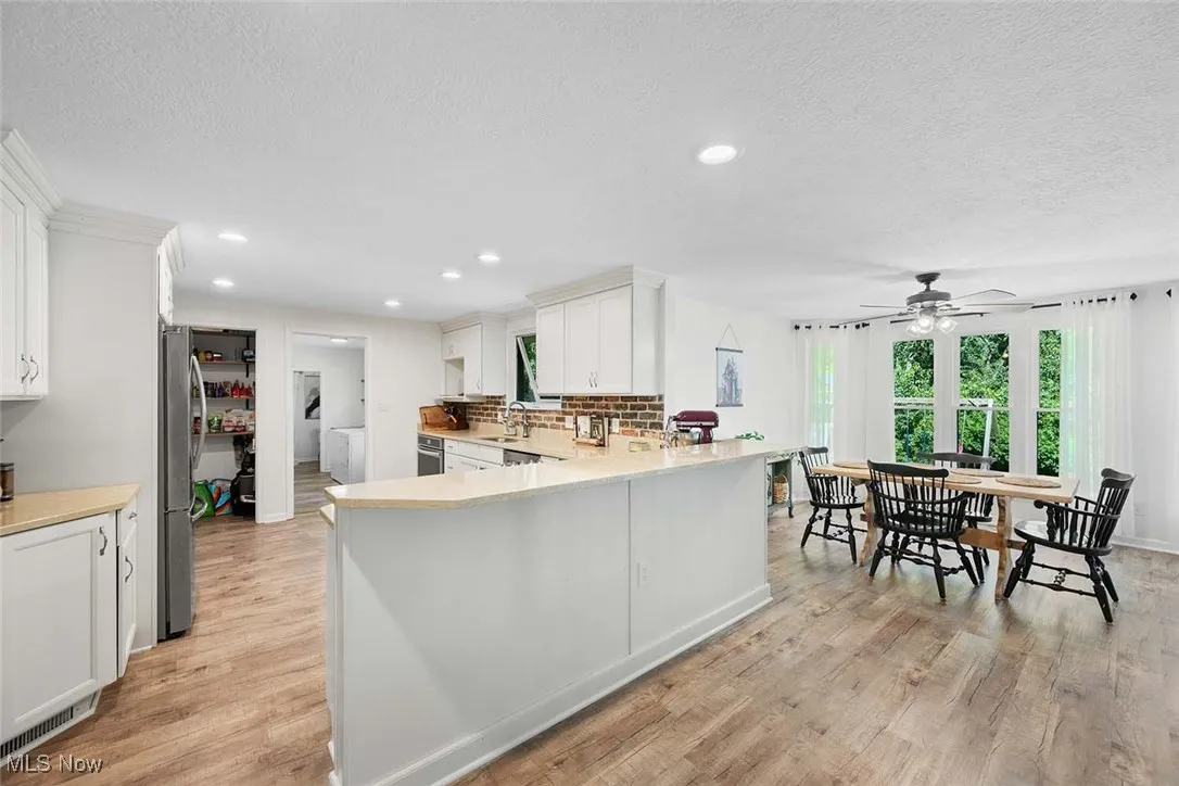 Kitchen featuring light countertops, white cabinetry, light wood-style flooring, a ceiling fan, and recessed lighting