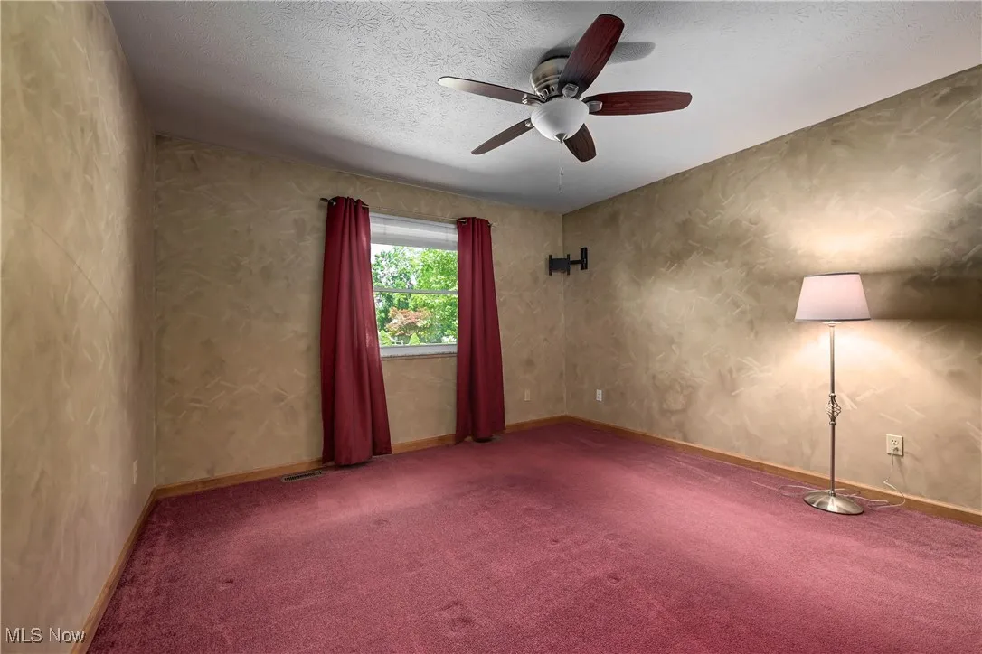 Carpeted spare room featuring a ceiling fan and a textured ceiling