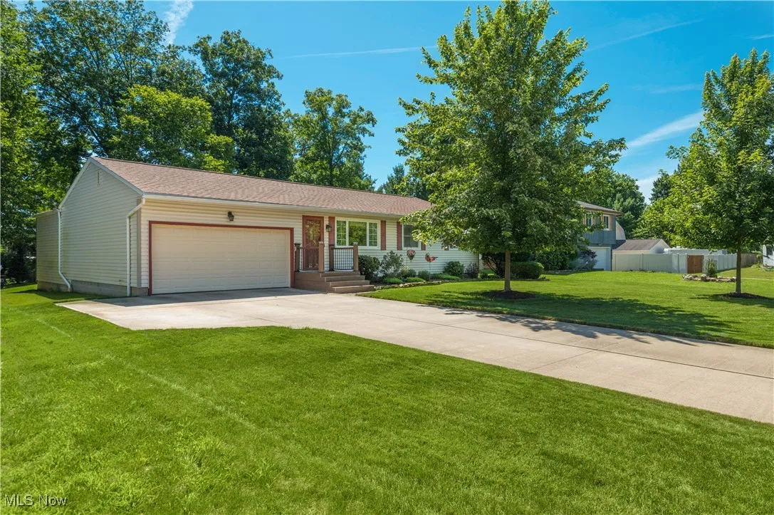 Ranch-style house featuring an attached garage, driveway, and a front yard
