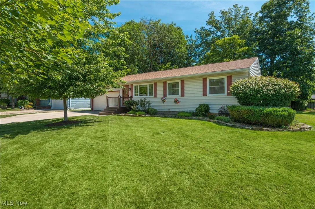 Ranch-style home with driveway, a front lawn, and an attached garage