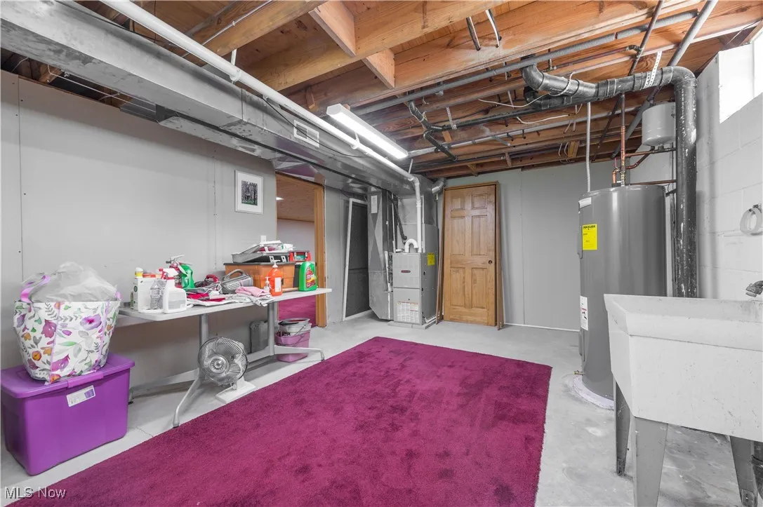 Unfinished basement featuring electric water heater and heating unit