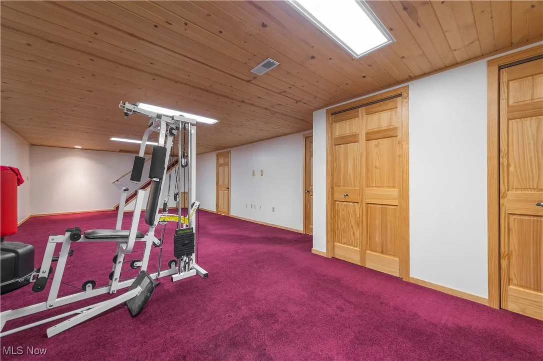 Workout room featuring wood ceiling and carpet floors