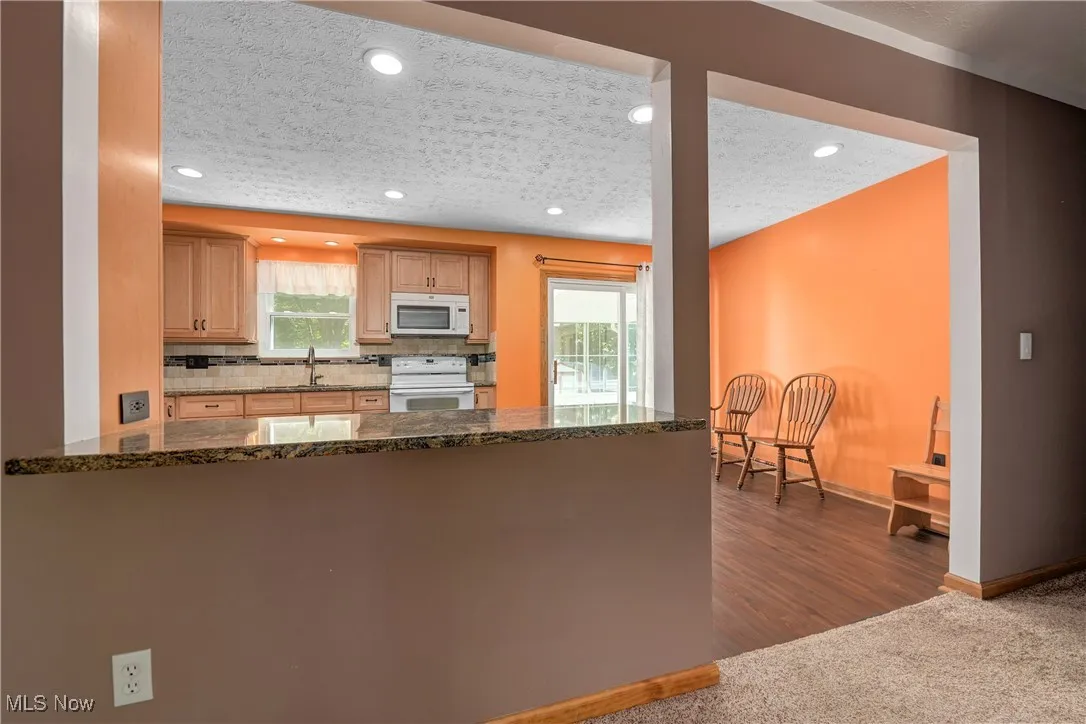 Kitchen featuring white appliances, carpet floors, plenty of natural light, a peninsula, and recessed lighting