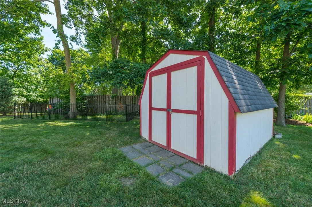 View of shed with a fenced backyard and view of scattered trees