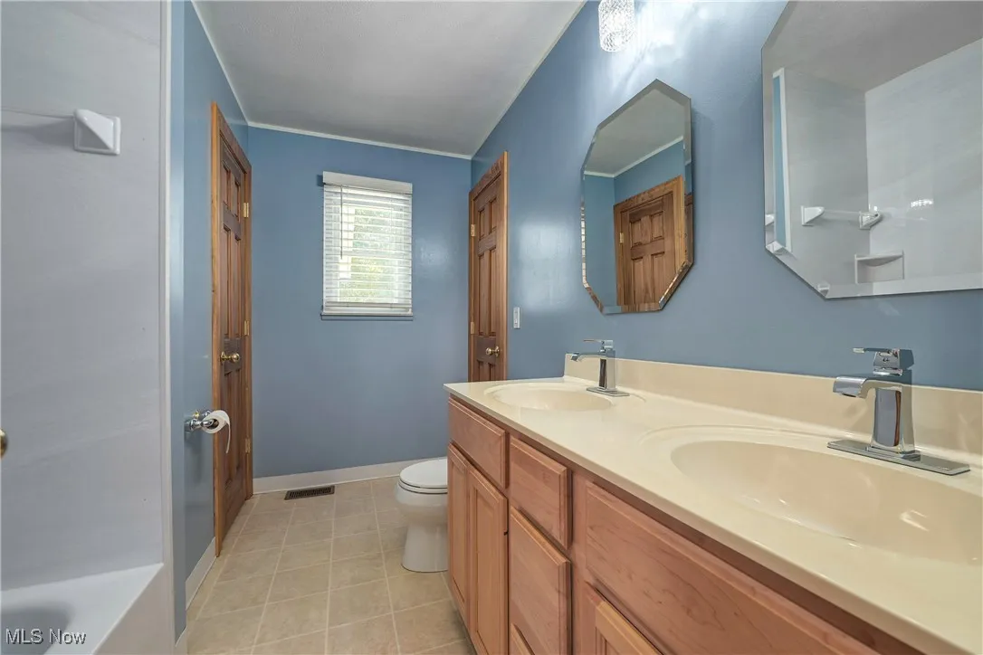 Bathroom with double vanity, a tub to relax in, and tile patterned flooring