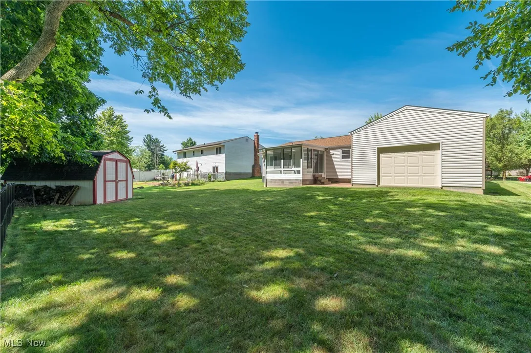 View of yard with a sunroom, a storage shed, and a garage