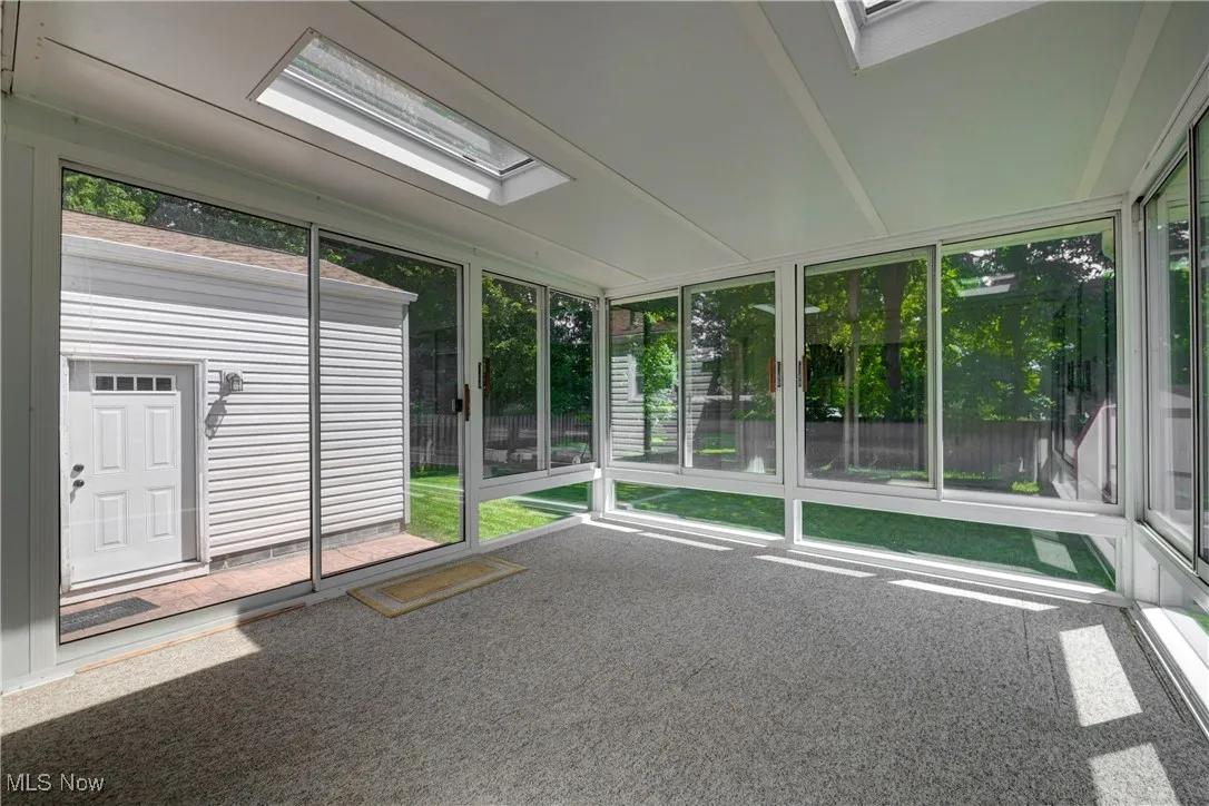 Unfurnished sunroom featuring a skylight
