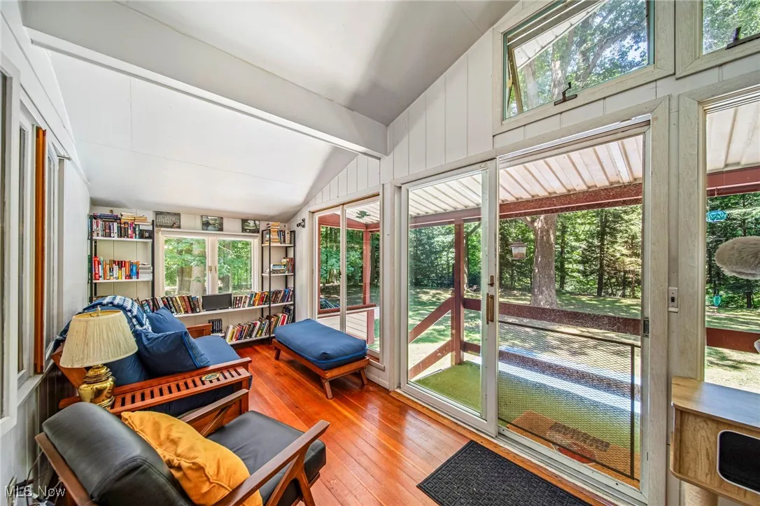 Sunroom / solarium featuring lofted ceiling and hardwood / wood-style floors