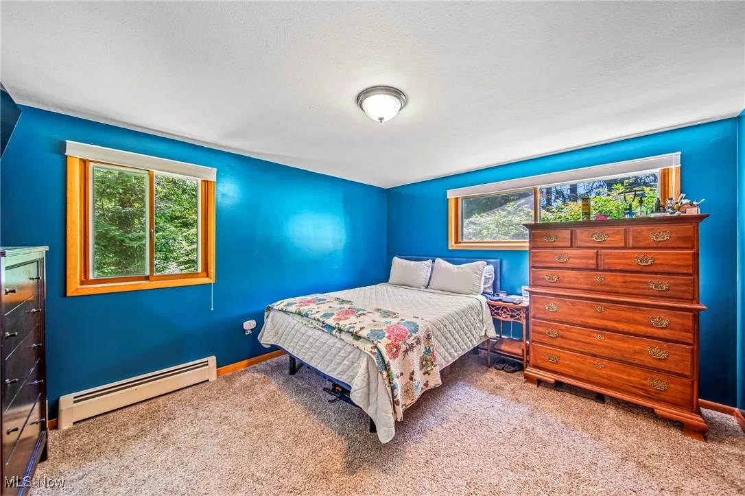 Carpeted bedroom featuring a baseboard heating unit and a textured ceiling