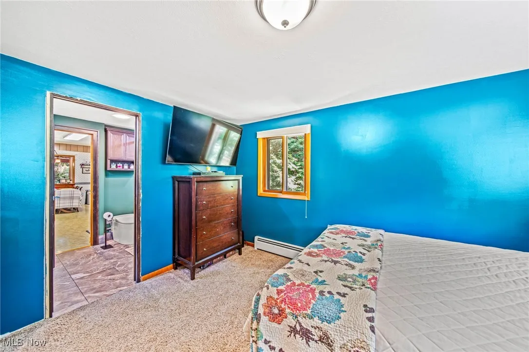 Bedroom with carpet flooring and baseboard heating