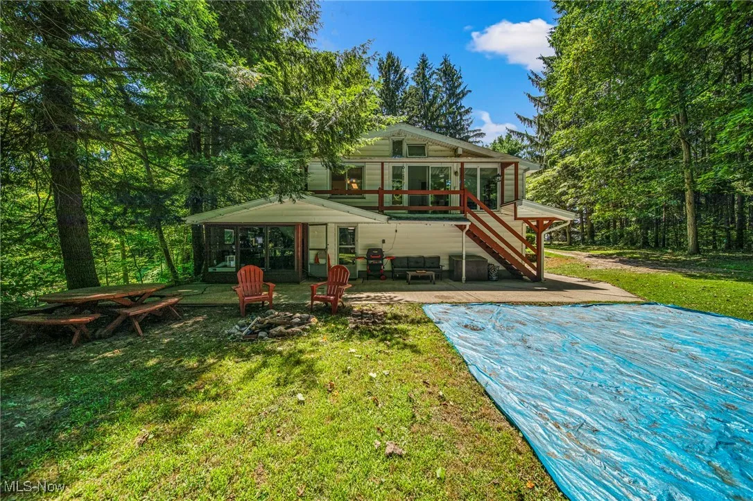Back of house featuring a sunroom, a patio area, stairs, and a wooden deck