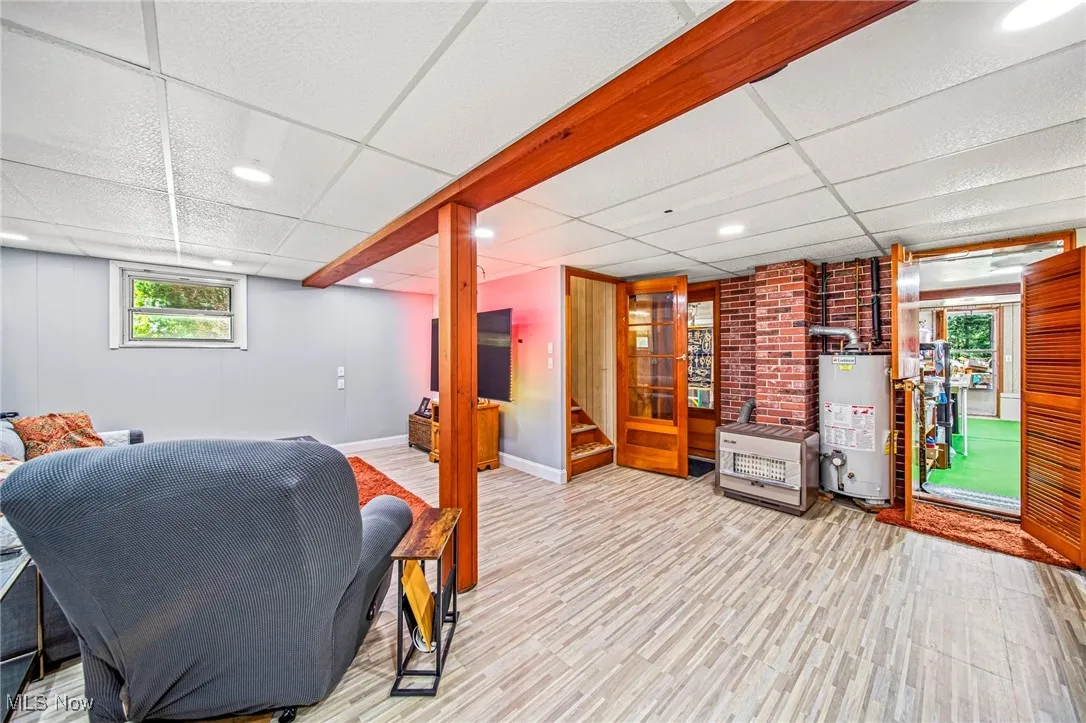 Living area featuring a paneled ceiling, wood finished floors, water heater, recessed lighting, and stairway