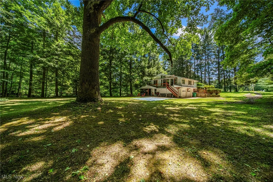 View of green lawn featuring stairway, a wooden deck, and a patio area